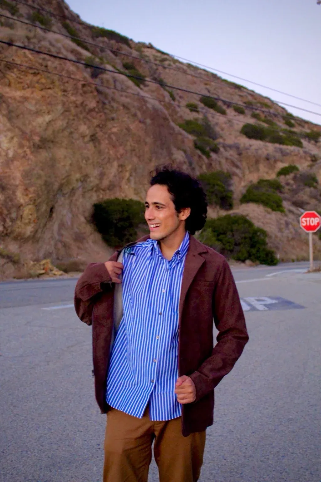 Rosan Sharma outdoors in California, smiling, jacket over one shoulder